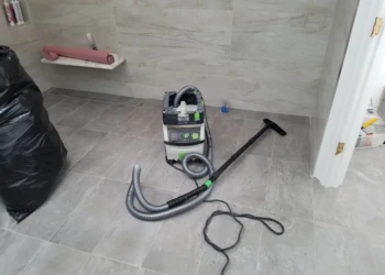 Compact wet/dry vacuum placed on tiled floor in a Carlisle kitchen during cabinet refinishing project
