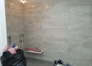 Newly installed light gray marble-patterned wall tiles and floor tiles in a master bathroom under renovation in Carlisle MA