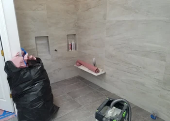Newly installed large gray tiles on walls and floor of master bathroom shower area with built-in niches in Carlisle MA