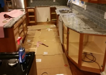 Kitchen cabinets being refinished in Concord MA, showing preparation and masking for a smooth finish.