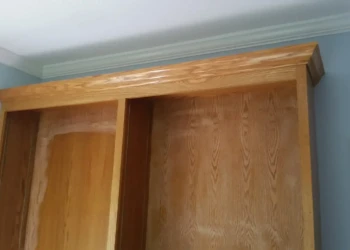 Wooden cabinet being sanded and prepared for refinishing.