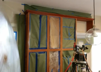 Cabinet refinishing with masking and sanding in progress.