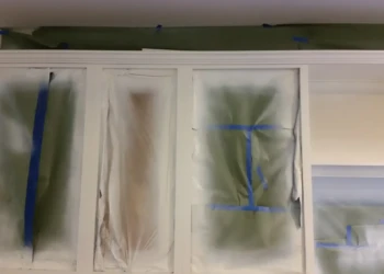 Cabinet refinishing in progress with masking and spray paint.