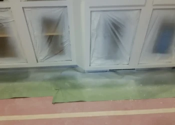 Cabinet refinishing with masking and sanding in progress.