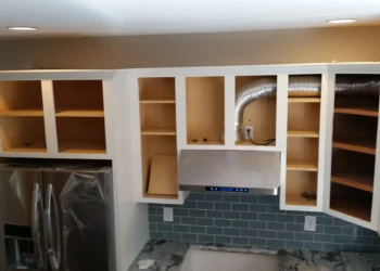 Kitchen cabinets being refinished with paint and new hardware.