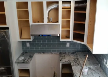 Kitchen cabinets being refinished with new paint and hardware.