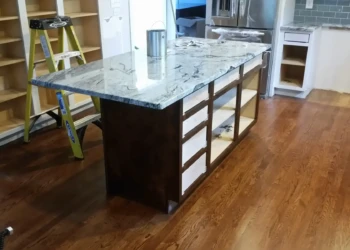 Kitchen island with newly refinished dark wood base and granite countertop in Concord MA.