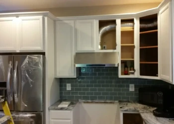 Kitchen cabinets being refinished in Concord MA, with some upper cabinets open showing preparation.