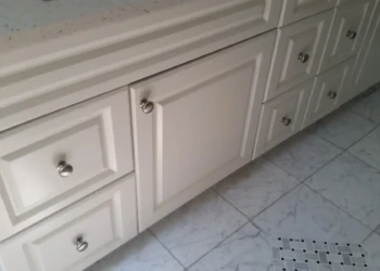 Refinished white kitchen cabinets in Concord MA, showing detailed craftsmanship and smooth paintwork.