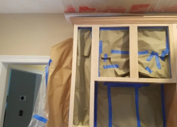 Unfinished kitchen cabinet frames masked with paper and painter’s tape for cabinet refinishing in Groton MA