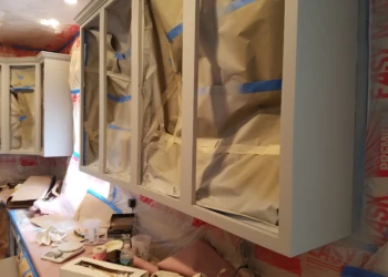 Kitchen cabinets with masking paper and tape during cabinet refinishing in Groton MA
