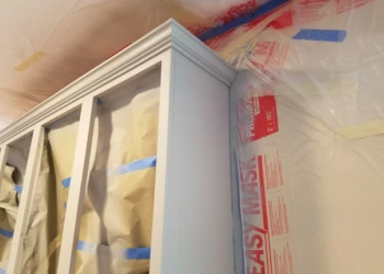 Kitchen cabinets masked with paper and plastic sheeting for cabinet refinishing preparation in Groton MA