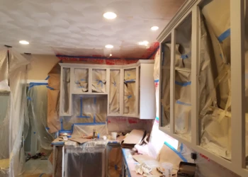 Kitchen cabinets masked and taped for refinishing in a Groton MA home, showing detailed surface preparation