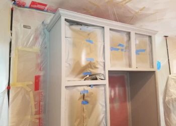 Kitchen cabinets masked and taped in plastic sheeting for refinishing preparation in Groton MA