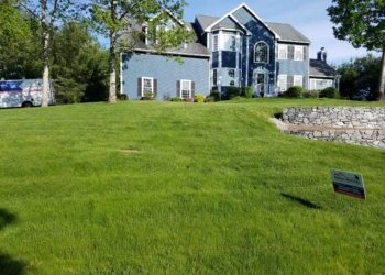 Blue two-story colonial style house with white window trims and green lawn in Groton Massachusetts