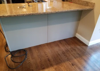 Refinished kitchen island cabinets with smooth light gray finish under granite countertop in Groton MA kitchen