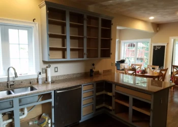 Kitchen cabinets in Groton MA partially refinished with blue-gray paint and open doors and drawers