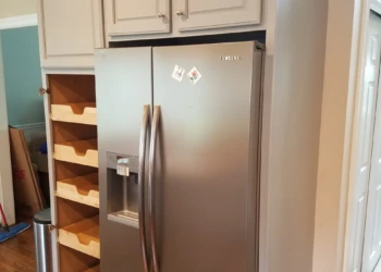 Refinished light gray kitchen cabinets with open storage shelves next to stainless steel refrigerator in Groton kitchen