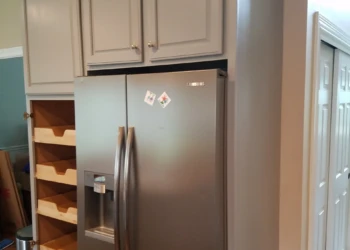 Refinished gray kitchen cabinets with shelves next to a stainless steel refrigerator in a Groton Massachusetts kitchen