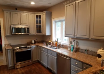 Gray painted kitchen cabinets with granite countertops, stainless steel appliances, and hardwood floors in Groton home