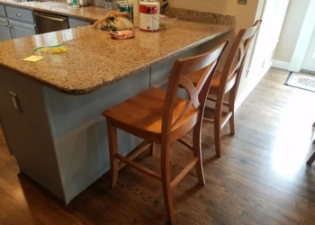 Refinished blue kitchen cabinets with granite countertop and wooden bar chairs in a Groton MA kitchen