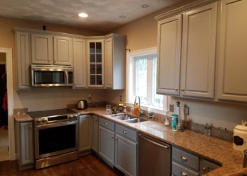 Gray two-tone kitchen cabinets with granite countertops and stainless steel appliances in Groton kitchen