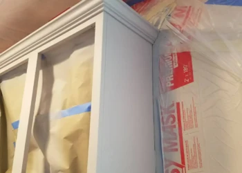 Partially refinished kitchen cabinet with protective masking in Groton MA home