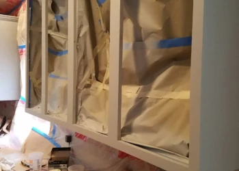 Partially refinished kitchen cabinets with protective paper in a Groton MA home