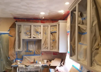 Kitchen cabinets covered with masking paper and tape for refinishing preparation in a Groton, MA home