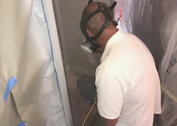 Worker wearing protective mask applying finish or paint to a kitchen cabinet in Groton, Massachusetts