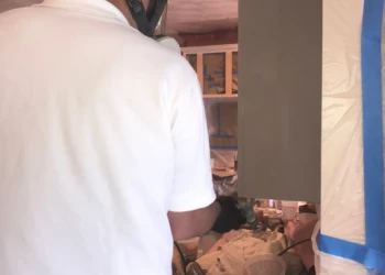 Worker spray-painting a kitchen cabinet in a Groton MA home during cabinet refinishing