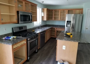Kitchen cabinets with open doors showing unfinished wood in Merrimack kitchen cabinet refinishing project