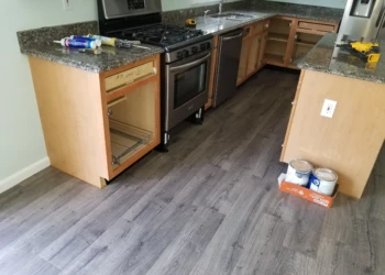 Kitchen cabinets in Merrimack NY with doors removed and tools on granite countertops during cabinet refinishing project