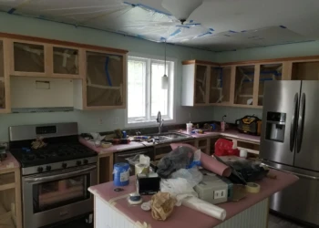 Kitchen cabinets with masking and protective coverings during cabinet refinishing project in Merrimack NH
