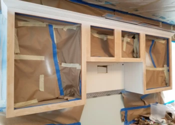 Unfinished kitchen cabinets masked with paper and tape during cabinet refinishing Merrimack NH project