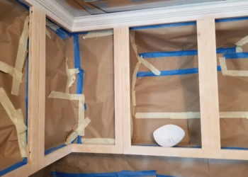 Unfinished wooden kitchen cabinet frames masked with protective paper and painter's tape in Merrimack, NH