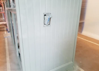 Close-up of newly installed white decorative bead board panel on kitchen island with a covered light switch opening in Merrimack