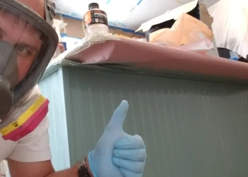 Contractor wearing respirator next to newly refinished beadboard island cabinet in Merrimack kitchen