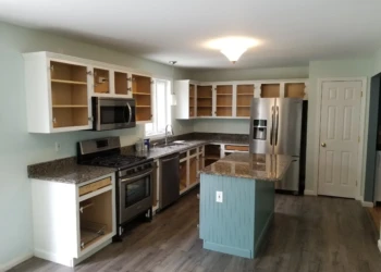 Kitchen interior showing white upper cabinets without doors and a blue bead board island with granite countertop in Merrimack, NH