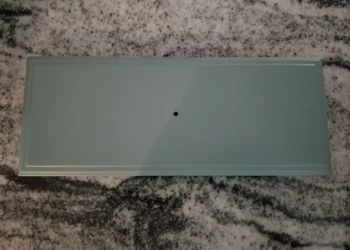 Refinished cabinet door panel in muted green on granite countertop, Merrimack cabinet painters project