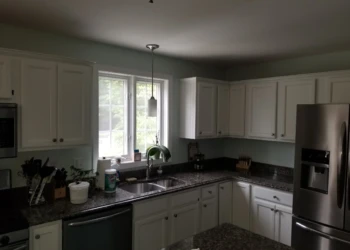 White refinished kitchen cabinets with dark granite countertops and stainless steel appliances in Merrimack NH