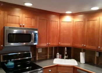 Cherrywood upper kitchen cabinets above stove and sink before refinishing in Nashua NH