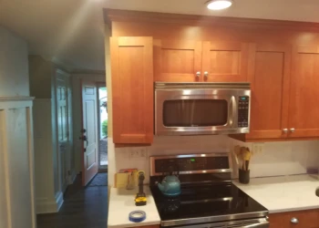 Cherry wood kitchen cabinets above microwave and range before refinishing in Nashua kitchen