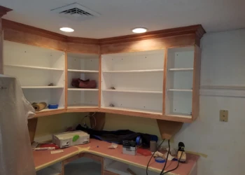 Partially finished kitchen cabinets with exposed wood and white interiors during cabinet refinishing in Nashua