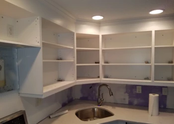 White painted kitchen cabinets without doors above a stainless steel sink in Nashua kitchen