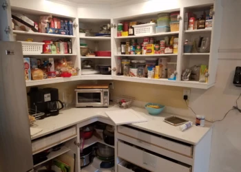 White kitchen cabinets with open doors showing shelves stocked with pantry items, drawers partially open, in Nashua NH kitchen
