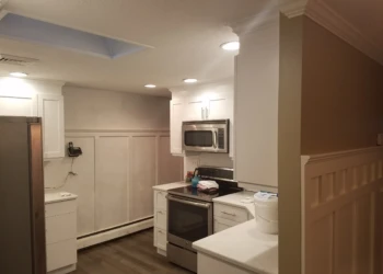 Newly refinished white kitchen cabinets with silver handles and stainless steel appliances in a Nashua kitchen