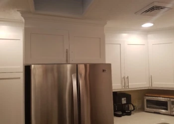 White refinished kitchen cabinets above and beside stainless steel refrigerator in Nashua kitchen