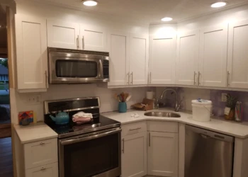 White kitchen cabinets surrounding stainless steel microwave and oven in a Nashua NH home kitchen
