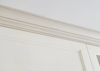 Close-up view of custom white crown molding above cabinet doors showing smooth finish and precise installation
